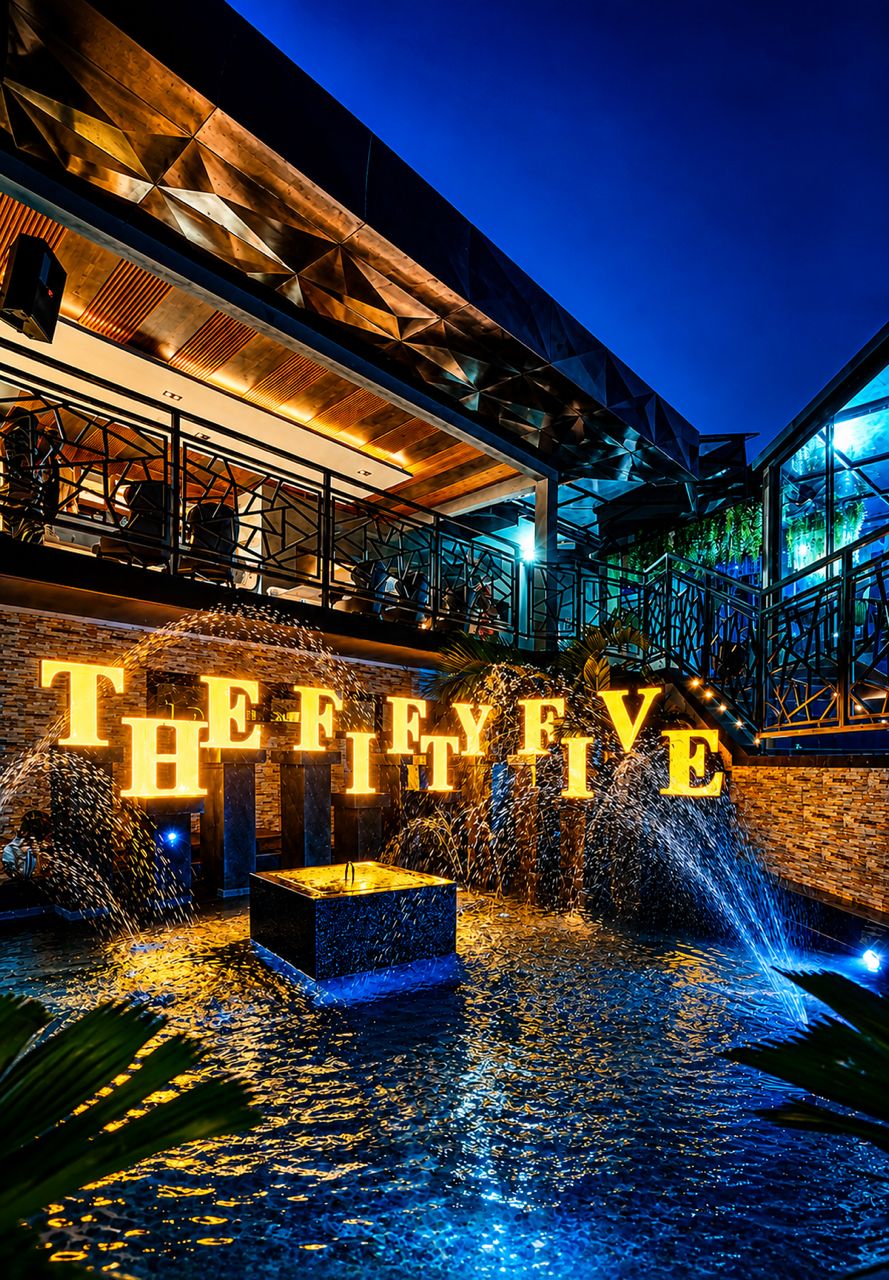 Façade illuminée de THE FIFTY FIVE avec son enseigne dorée et sa fontaine